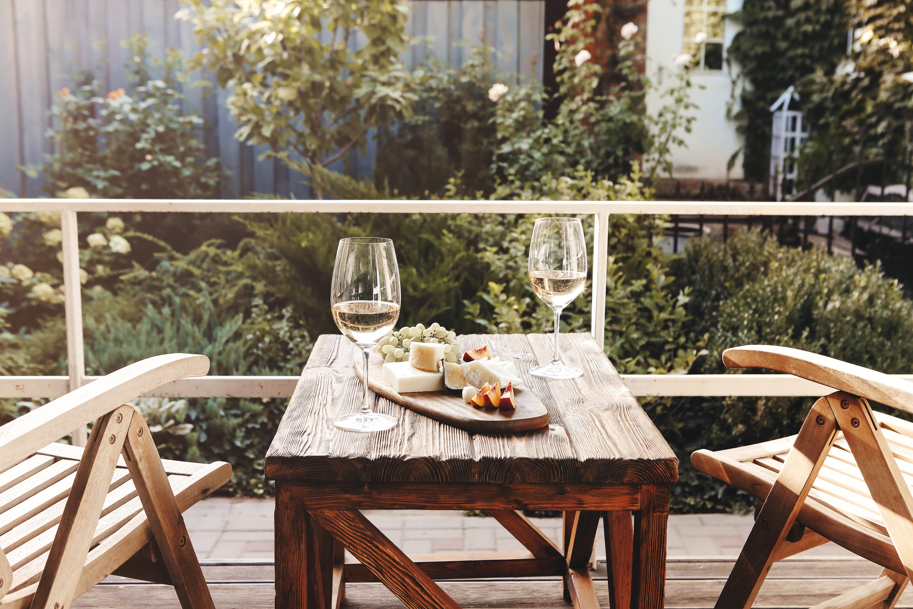 Due calici di vino bianco e formaggi su tavolo all’aperto per una cena romantica