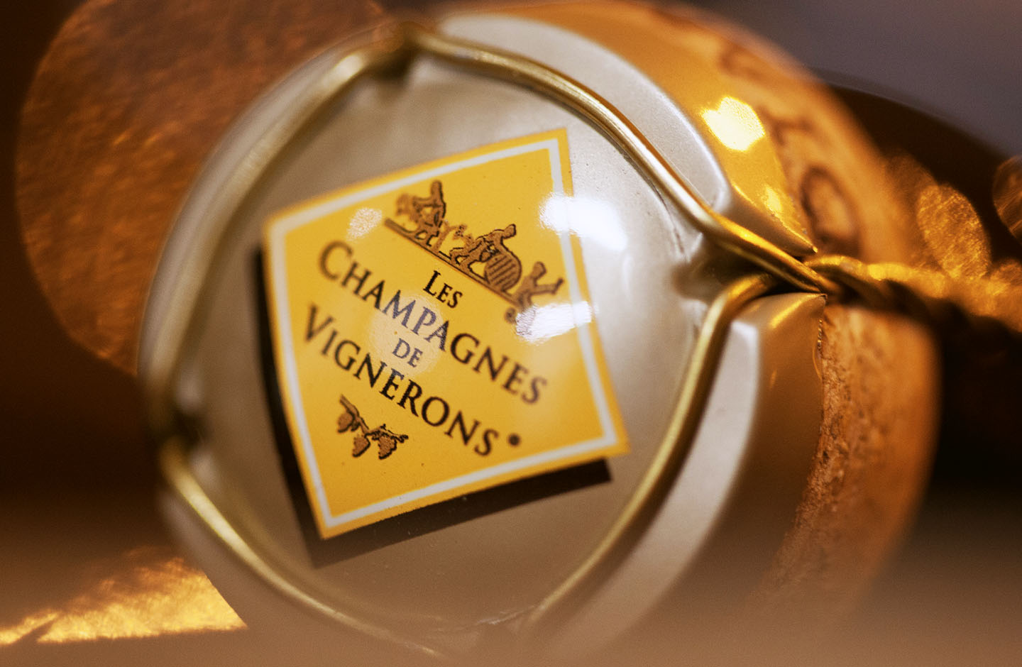 Tappo di una bottiglia di Champagne con etichetta 'Les Champagnes de Vignerons', simbolo dell’eccellenza artigianale francese