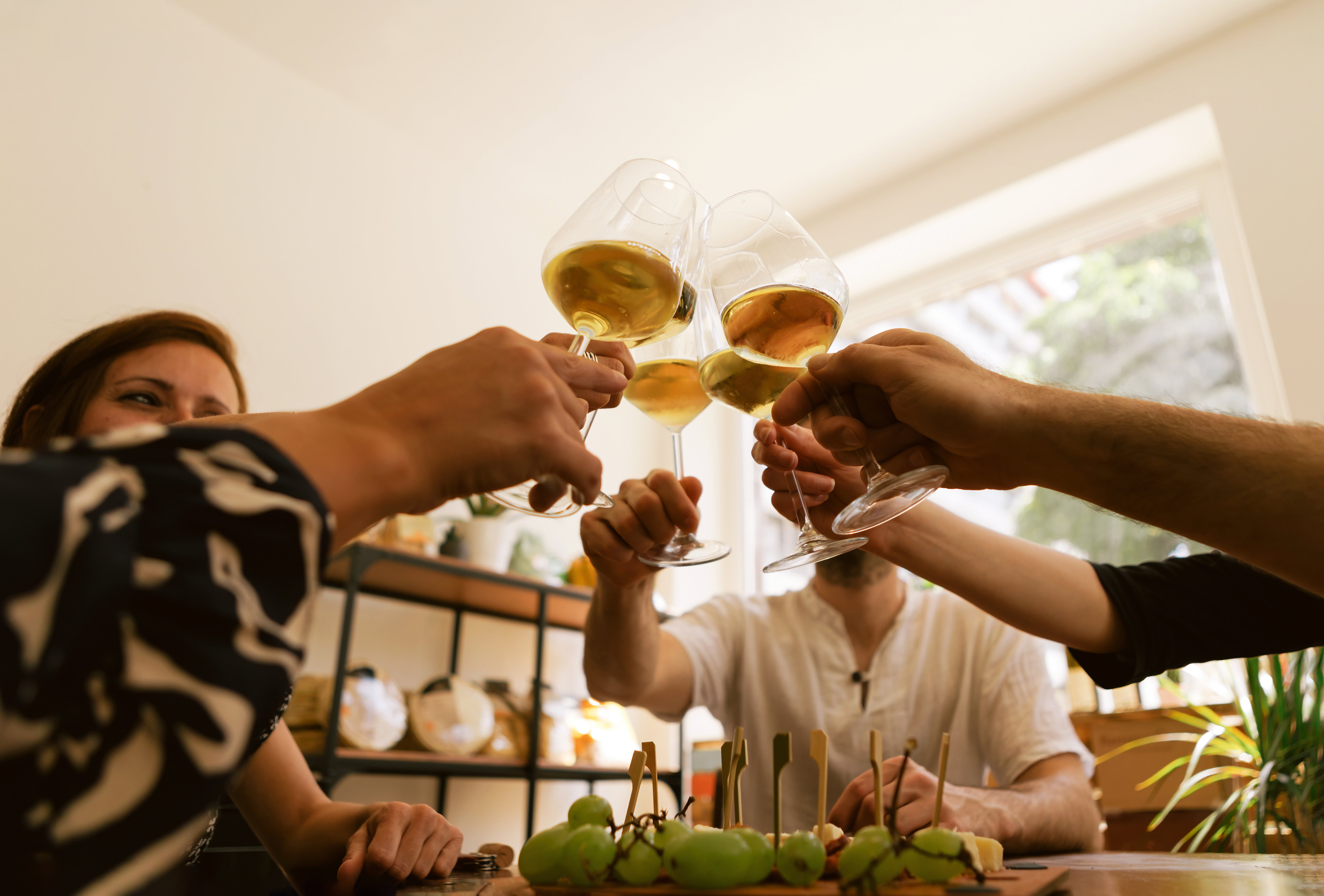 Brindisi con calici di vino bianco tra amici, ideale per l’aperitivo.